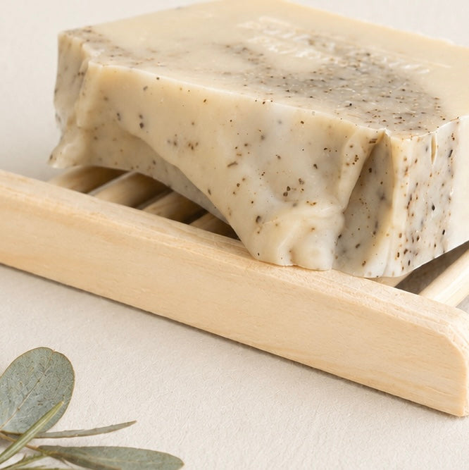 Natural handmade tea tree and eucalyptus soap resting on a wooden soap dish. Australian cold process soap with pure essential oils and a long-lasting bar.
