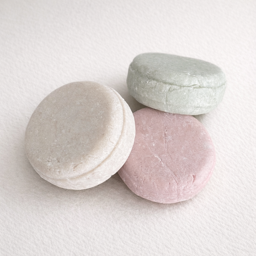 Medika Organics solid shampoo bars in light gray, pink, and white on a white background